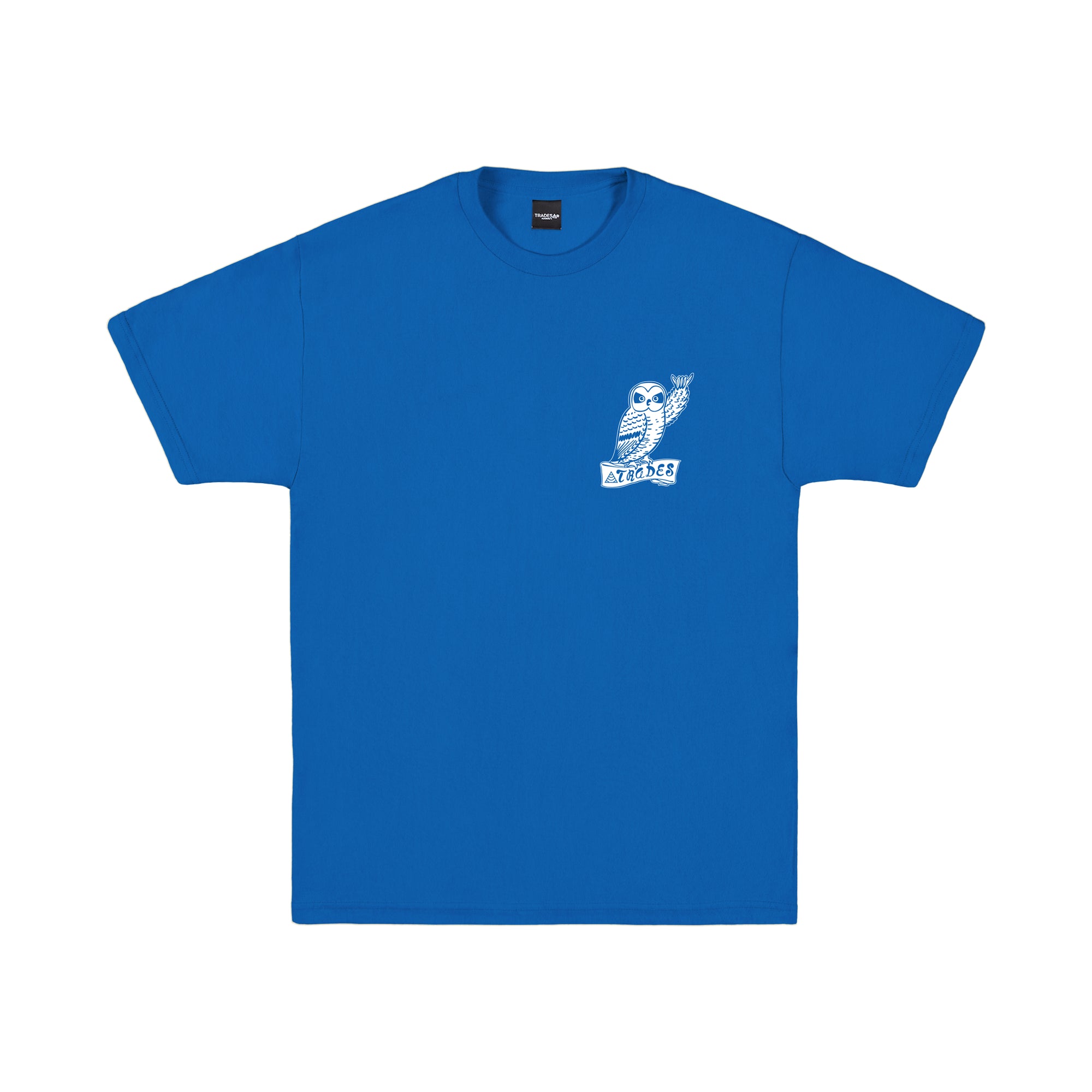 The front of a royal blue t-shirt with a small white illustration of an owl on the left chest, raising its wing to shaka, and a banner below it with the &quot;TRADES&quot;